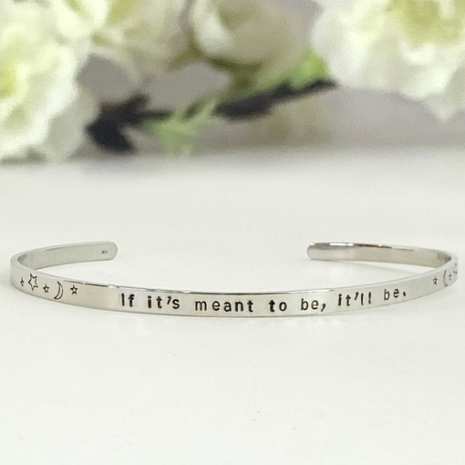 A thin silver Cuff Brace If Meant To Be engraved with the words “If it’s meant to be, it’ll be,” flanked by stars and crescent moons. Read more at Stamping Cat Studio (stampingcatstudio.com).