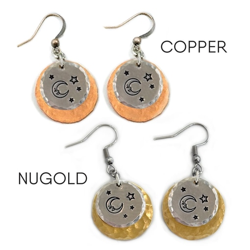 The Man In The Moon ear metals feature two pairs of dangle earrings, each with overlapping hammered discs—a larger copper or yellow-gold disc and a smaller silver disc stamped with moon and star motifs. Read more at Stamping Cat Studio (stampingcatstudio.com).