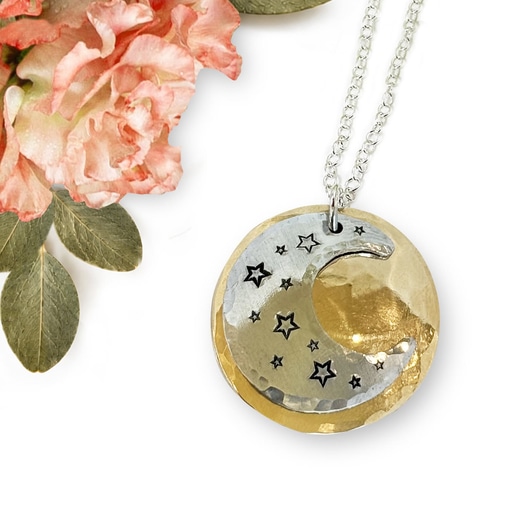 The Dreamy Sun Moon Stars neck main is a round, dual-layered necklace on a silver chain, featuring a silver crescent moon with stars atop a textured gold-tone disc, accented with a peach-colored flower and green leaves. Read more at Stamping Cat Studio (stampingcatstudio.com).