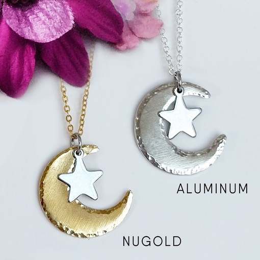 Two handcrafted Moon And Star Necklace pieces are displayed: one NUGOLD (gold-toned) on a gold chain, and one ALUMINUM (silver-toned) on a silver chain. A purple flower decorates the top left corner. Read more at Stamping Cat Studio (stampingcatstudio.com).