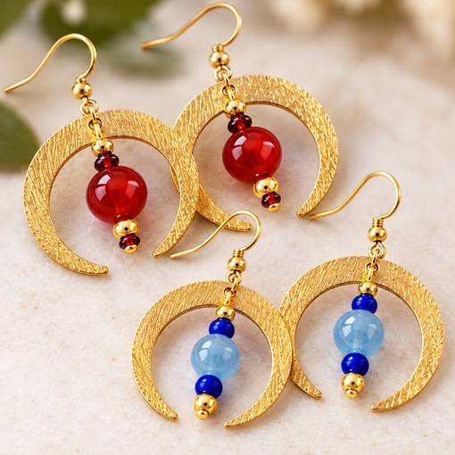 Two pairs of Boho Crescent Moon Semi-Precious Bead Ear main earrings rest on a textured surface, with the top pair featuring red beads and the bottom pair showcasing light and dark blue beads, all hanging from gold wire hooks. Read more at Stamping Cat Studio (stampingcatstudio.com).